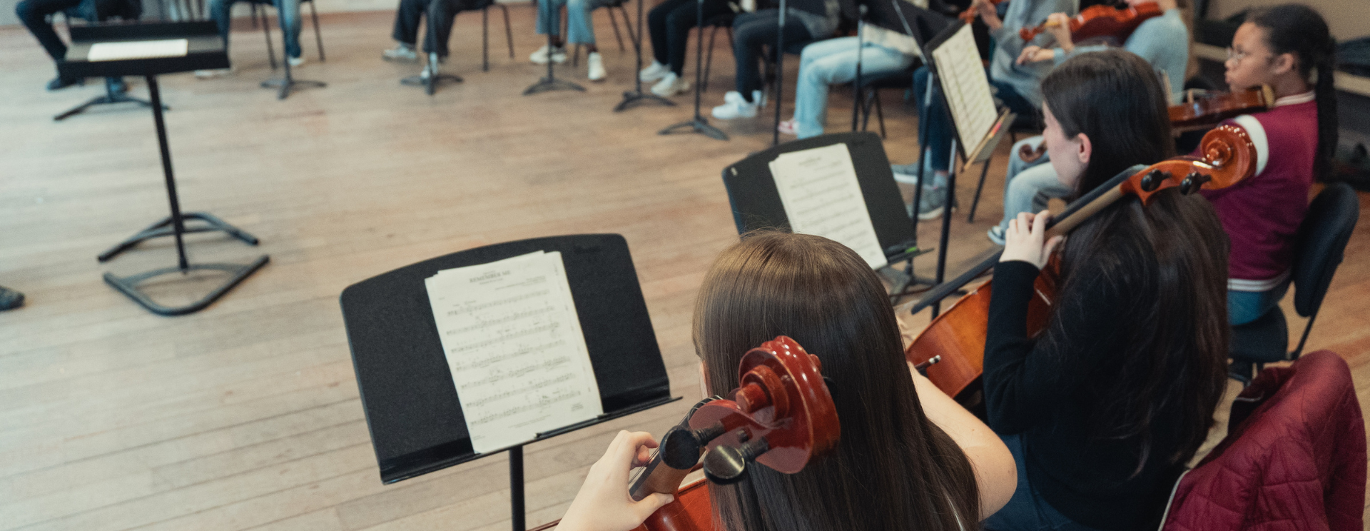 groupe d'enfants et adolescents, assis sur des chaises formant un cercle et jouant chacun d'un instruments
